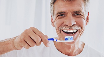 Man with dentures brushing his teeth