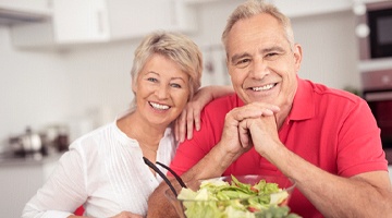 Older couple smiling after preparing a salad