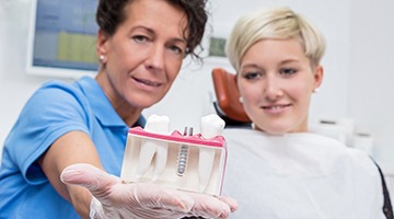 Implant dentist in Colleyville showing patient a tooth replacement model