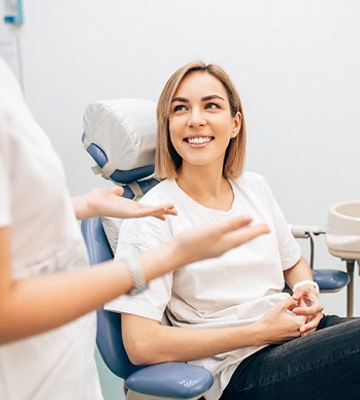 A dental employee speaking with a smiling patient.