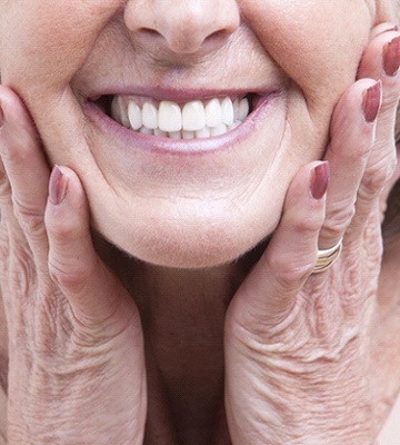Woman with dental implants in Colleyville touching her cheeks
