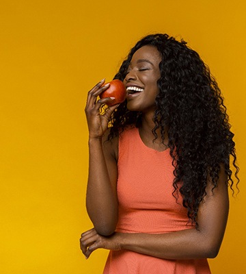 Woman with dental implants in Colleyville eating an apple