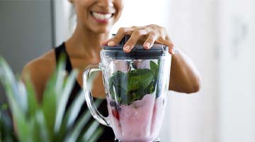 Woman with dental implants in Colleyville using a blender