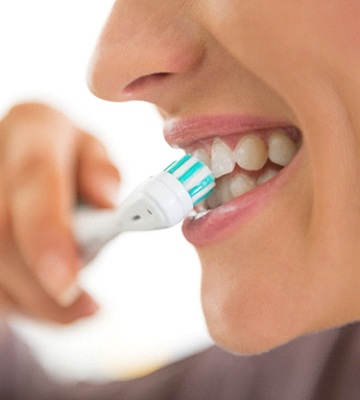 Woman brushing her teeth to prevent dental emergencies in Colleyville