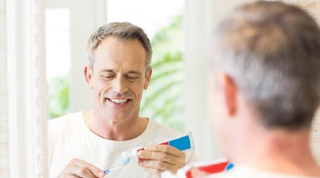 Man applying toothpaste to a toothbrush
