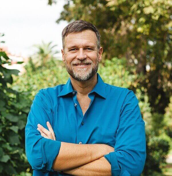 Older man in blue button down shirt smiling outdoors