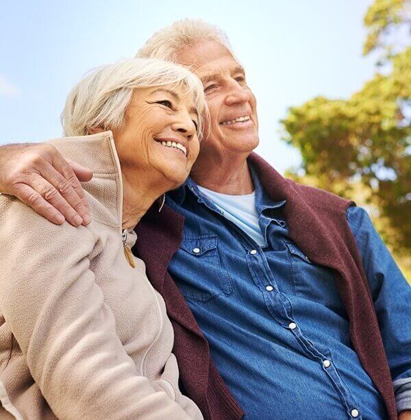 Smiling older man and woman sitting close together outdoors