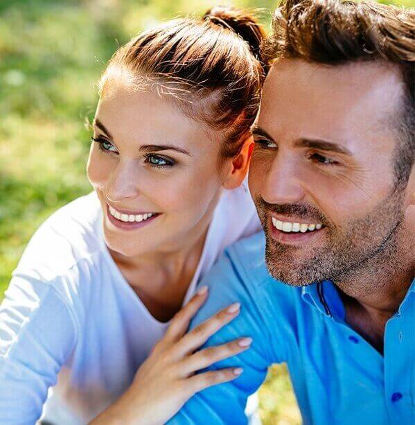 Smiling young man and woman holding each other outdoors