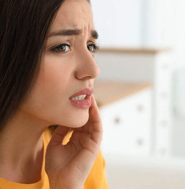 Young woman holding her cheek in pain