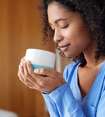 Woman smelling cup of coffee