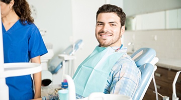 Man smiling in dental chair wearing plaid shirt