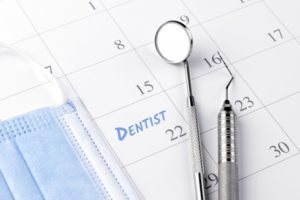 "dentist appointment" written on calendar with a mask and dental instruments sitting on it