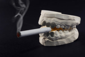 White teeth impressions smoking cigarette on dark background 