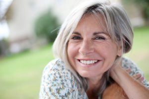 Woman with dental implants smiling while enjoying the sunshine.