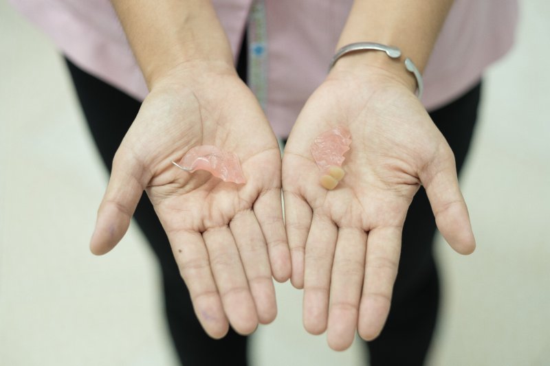 Hands holding a broken denture